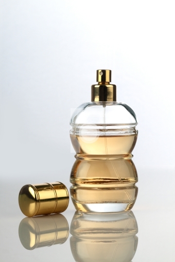 Beautiful Perfume Bottle On White Reflective Surface