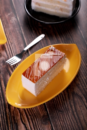 Caramel Pastry Cheese Cake on a Yellow Plate with Fork on Wooden