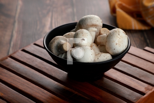 Fresh Uncooked Organic Button Mushrooms in a Black Bowl
