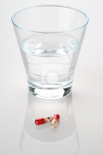 Glass of Water and Medicine Capsules