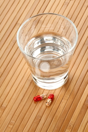 Glass of Water and Medicine Pills on Wooden Background