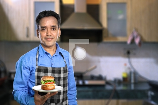 Indian Male Chef with a Burger in a Kitchen