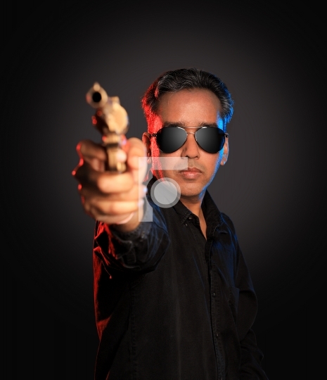Indian Man with sunglasses and gun on dark background