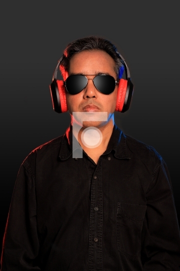 Indian man with sunglasses and wireless headphones on grey backg
