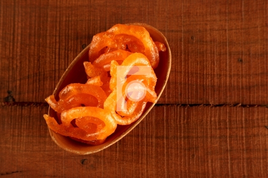 Indian Sweet Jalebi in a handmade pottery bowl on wooden backgro