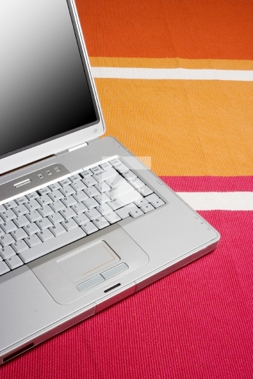 Laptop on a colorful rug, work at home concept