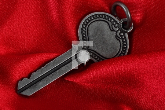 Old vintage key in red satin cloth background