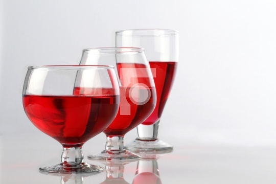 Three Red Wine Glasses on White Reflective Background