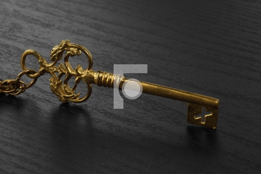 Golden Antique Key on black wooden background