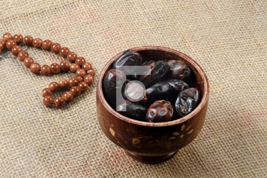 Ramadan fresh dates in a wooden bowl with rosary